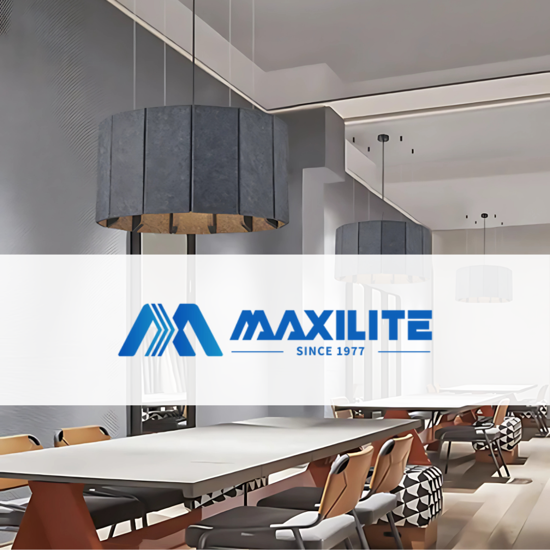 Modern pendant lighting by Maxilite installed above a long communal table in a contemporary office or dining space with designer chairs and minimal decor.